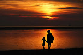 Families walking along a quiet seafront promenade at sunset